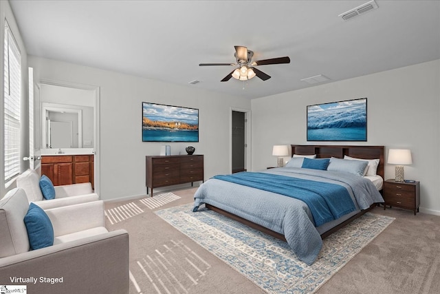 bedroom with light colored carpet, baseboards, a ceiling fan, a sink, and ensuite bathroom
