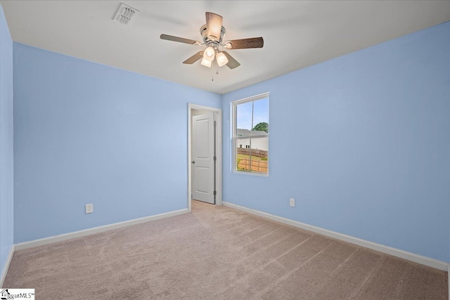 carpeted empty room with a ceiling fan and baseboards