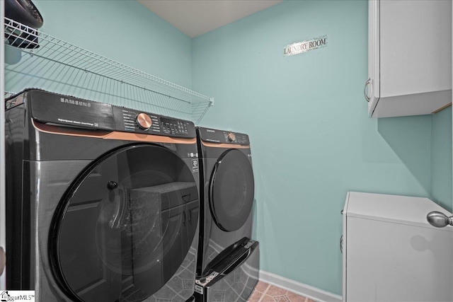 clothes washing area featuring cabinet space, washer and dryer, baseboards, and tile patterned floors