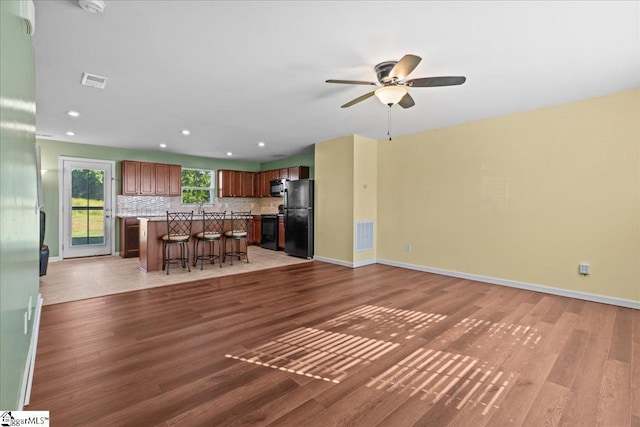 unfurnished living room featuring light wood-style flooring, a ceiling fan, recessed lighting, and baseboards