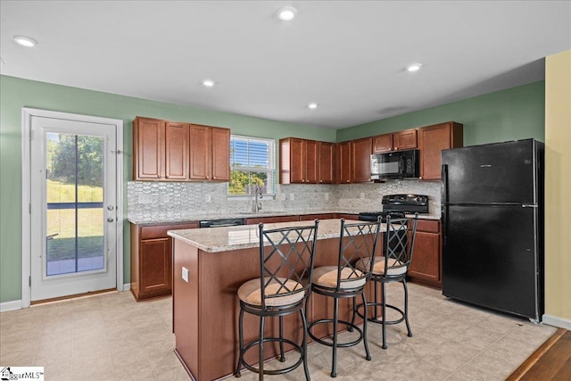 kitchen with black appliances, backsplash, baseboards, a sink, and a center island