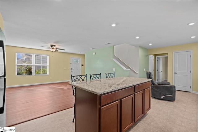 kitchen with open floor plan, ceiling fan, a center island, a breakfast bar, and recessed lighting