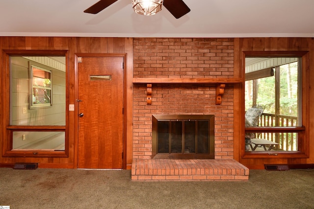 200 Lavonne Ave, Easley, SC 29642 - unfurnished living room featuring ornamental molding, carpet, wood walls, ceiling fan, and a brick fireplace