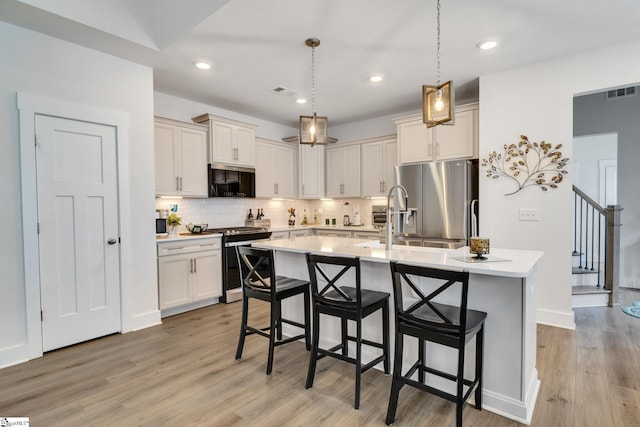 1560 Shallons Ct, Spartanburg, SC 29301 - kitchen with appliances with stainless steel finishes, light wood-type flooring, a kitchen bar, decorative backsplash, and light countertops