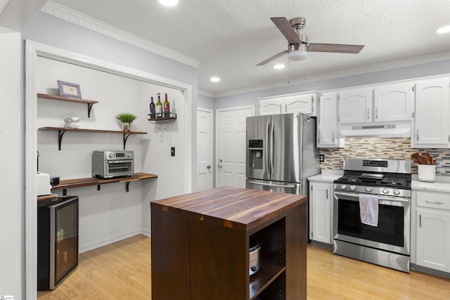 kitchen featuring appliances with stainless steel finishes, under cabinet range hood, butcher block counters, open shelves, and ornamental molding