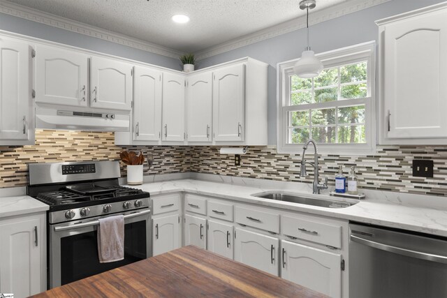kitchen with appliances with stainless steel finishes, under cabinet range hood, a sink, white cabinetry, and a textured ceiling