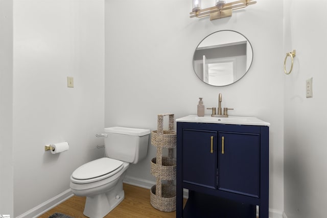bathroom featuring wood finished floors, baseboards, toilet, and vanity