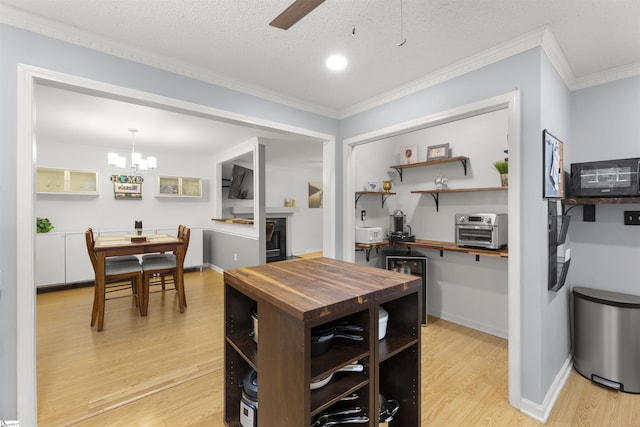 dining room featuring light wood-style floors, ornamental molding, ceiling fan, a chandelier, and beverage cooler