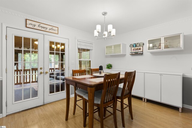 dining area with a chandelier, french doors, crown molding, and light wood-type flooring
