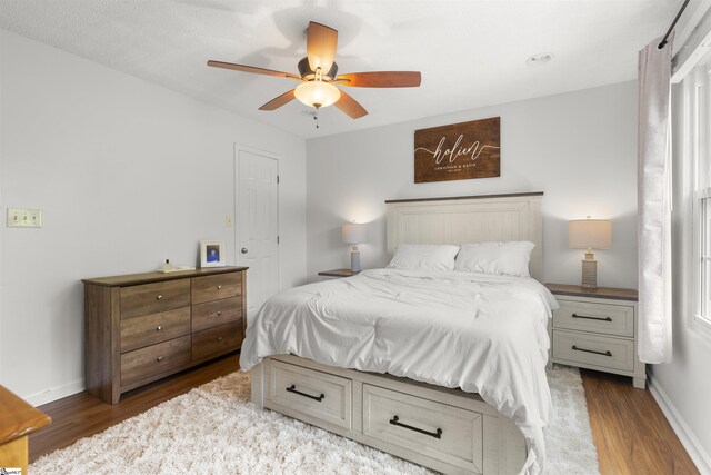 bedroom featuring wood finished floors, baseboards, and a ceiling fan
