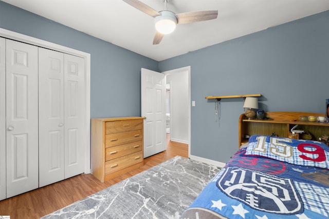 bedroom with a closet, wood finished floors, a ceiling fan, and baseboards
