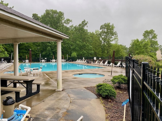 community pool with fence, a patio, a community hot tub, and view of scattered trees