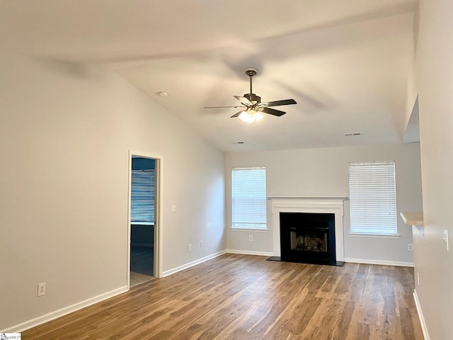 unfurnished living room featuring ceiling fan, vaulted ceiling, wood finished floors, and baseboards