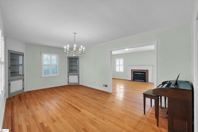 dining area featuring a chandelier, light wood-style flooring, baseboards, and a fireplace