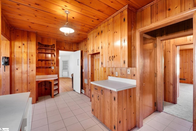 kitchen featuring light tile patterned floors, wood walls, wooden ceiling, light countertops, and decorative light fixtures