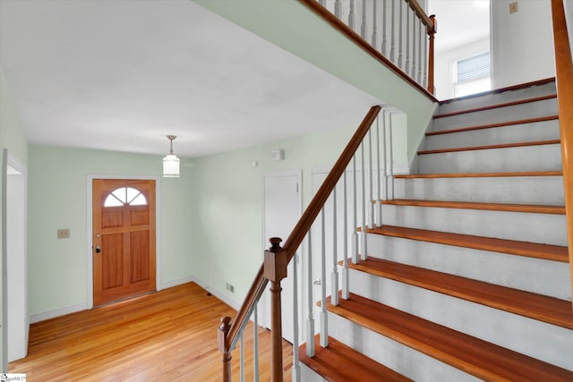 entrance foyer with light wood-style floors, stairs, healthy amount of natural light, and baseboards