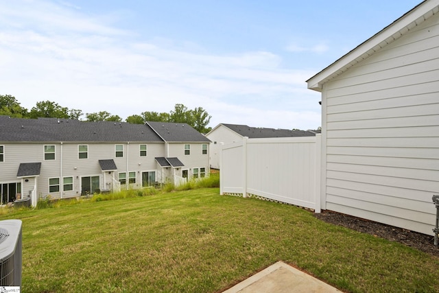 view of grassy yard with a residential view and central AC unit