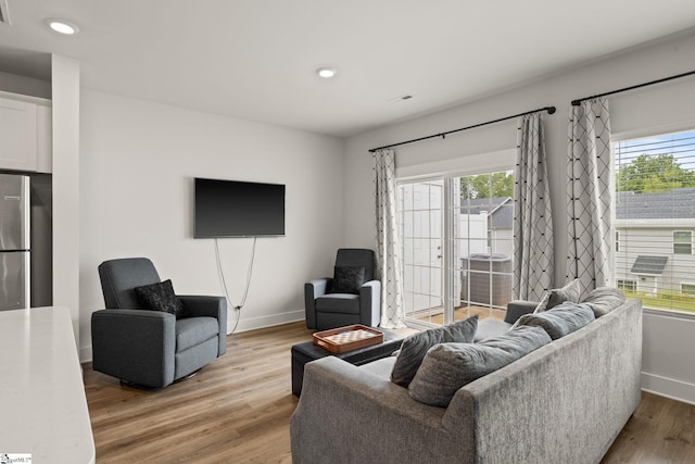 living area with baseboards, light wood finished floors, and recessed lighting