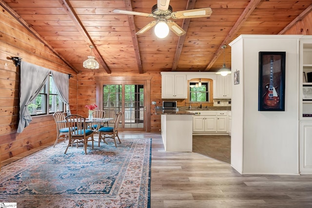 dining area with wood ceiling, light wood finished floors, wooden walls, and ceiling fan