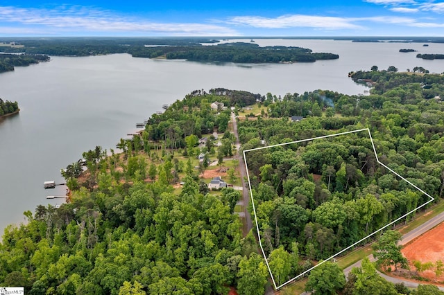 aerial view of property's location featuring a nearby body of water, property boundaries highlighted, and a heavily wooded area