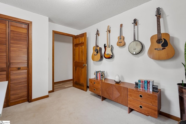 bedroom with light carpet, a closet, a textured ceiling, and baseboards