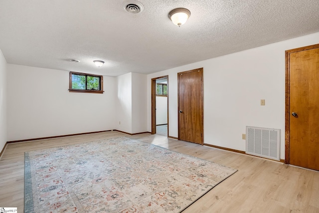 unfurnished room featuring a textured ceiling, light wood-style flooring, and baseboards