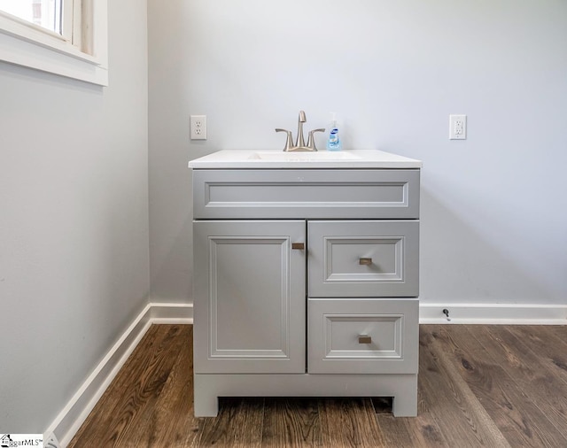 bathroom view of baseboards, wood finished floors, and vanity