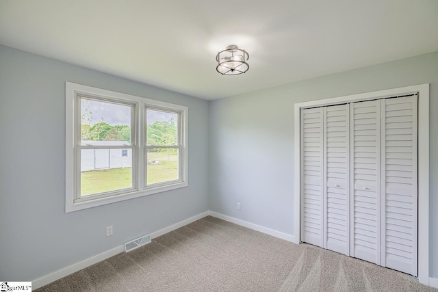 unfurnished bedroom with baseboards, carpet floors, and a closet