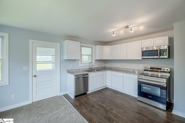 kitchen featuring stainless steel appliances, a sink, white cabinetry, dark wood-style floors, and baseboards
