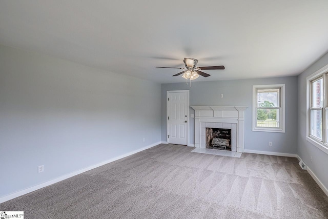 unfurnished living room with ceiling fan, carpet flooring, a tile fireplace, and baseboards