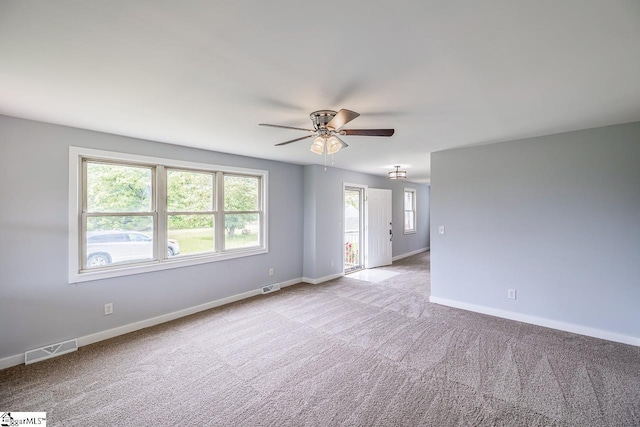 carpeted spare room with a ceiling fan and baseboards