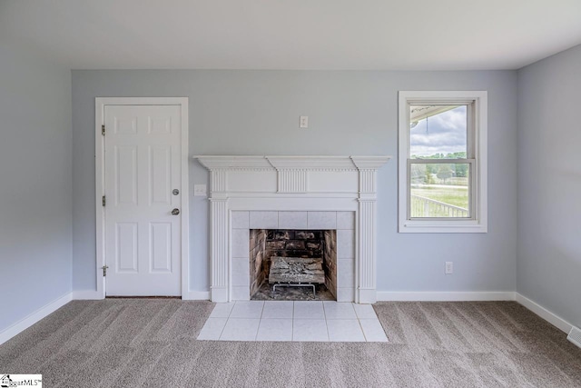unfurnished living room featuring carpet floors, a tile fireplace, and baseboards