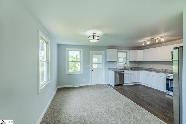 kitchen with appliances with stainless steel finishes, a sink, baseboards, white cabinets, and dark wood-style flooring