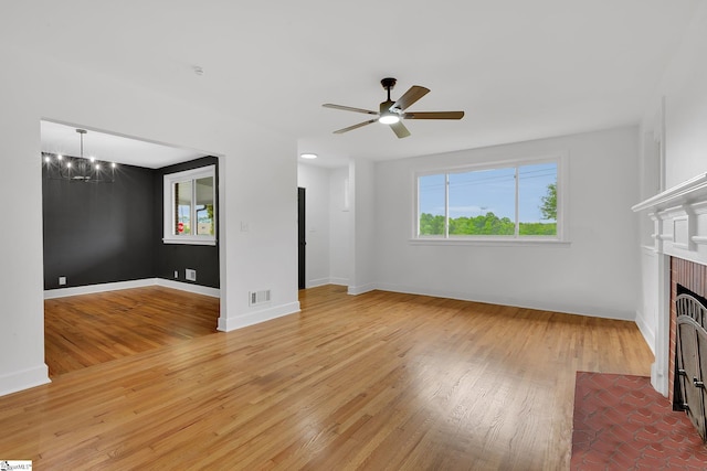 3902 Old Buncombe Rd, Greenville, SC 29617 - unfurnished living room with healthy amount of natural light, a chandelier, light wood-type flooring, and a brick fireplace