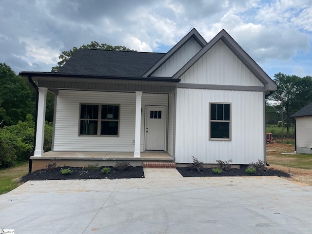 view of front of house with a porch, roof with shingles, and board and batten siding