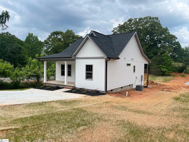 view of side of property with crawl space, a porch, a shingled roof, and a yard