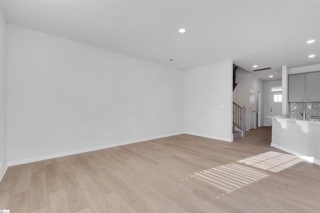 307 E Compass Way, Easley, SC 29640 - unfurnished living room featuring light wood-type flooring, a sink, stairs, recessed lighting, and baseboards