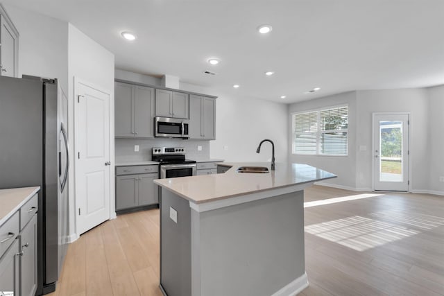 307 E Compass Way, Easley, SC 29640 - kitchen with appliances with stainless steel finishes, gray cabinetry, light wood finished floors, tasteful backsplash, and an island with sink