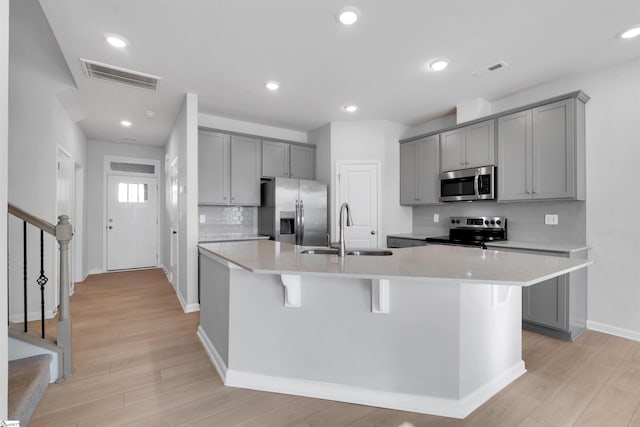 307 E Compass Way, Easley, SC 29640 - kitchen featuring appliances with stainless steel finishes, a sink, gray cabinets, a center island with sink, and tasteful backsplash