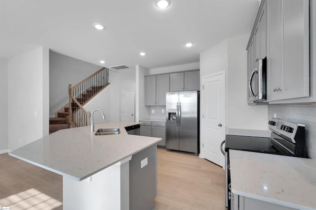 307 E Compass Way, Easley, SC 29640 - kitchen featuring stainless steel appliances, a sink, gray cabinetry, light wood finished floors, and a kitchen island with sink