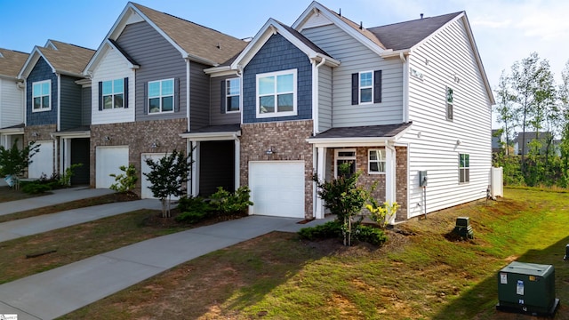view of property featuring a garage, driveway, brick siding, and a front lawn