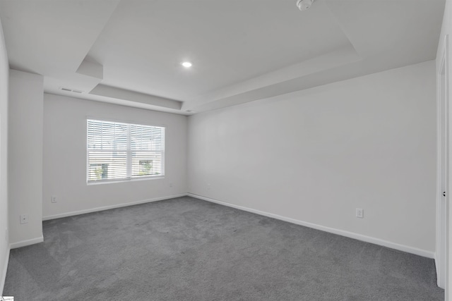spare room featuring a tray ceiling, baseboards, and carpet flooring