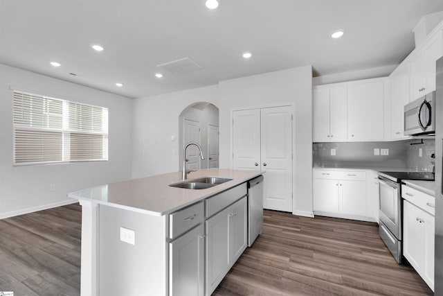 kitchen featuring a sink, stainless steel appliances, arched walkways, dark wood finished floors, and recessed lighting