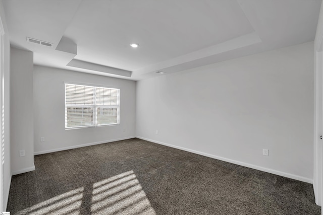 spare room featuring a tray ceiling, dark carpet, baseboards, and recessed lighting