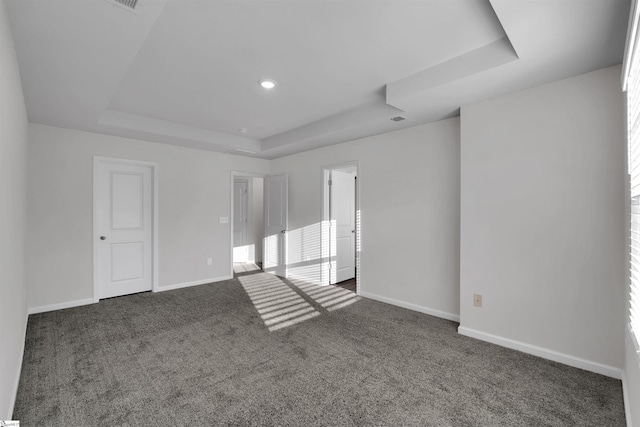 empty room featuring a tray ceiling, carpet flooring, and baseboards