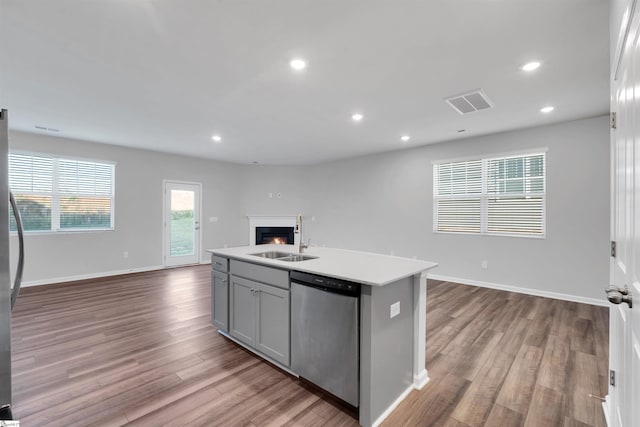 kitchen featuring open floor plan, appliances with stainless steel finishes, a sink, wood finished floors, and light countertops
