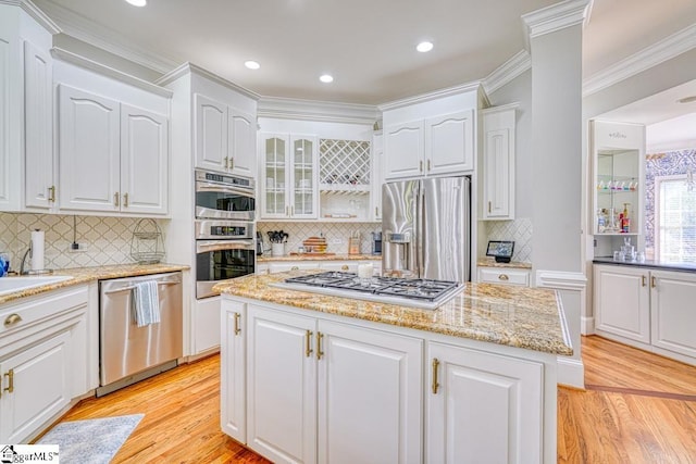 kitchen with stainless steel appliances, a center island, light wood-style floors, decorative backsplash, and white cabinetry
