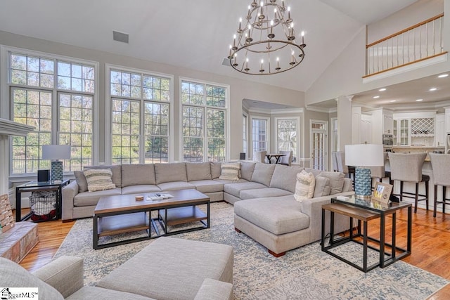 living area featuring high vaulted ceiling, light wood-style flooring, and a chandelier