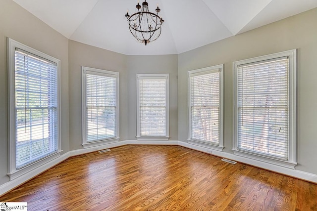 unfurnished dining area featuring lofted ceiling, a chandelier, wood finished floors, and baseboards