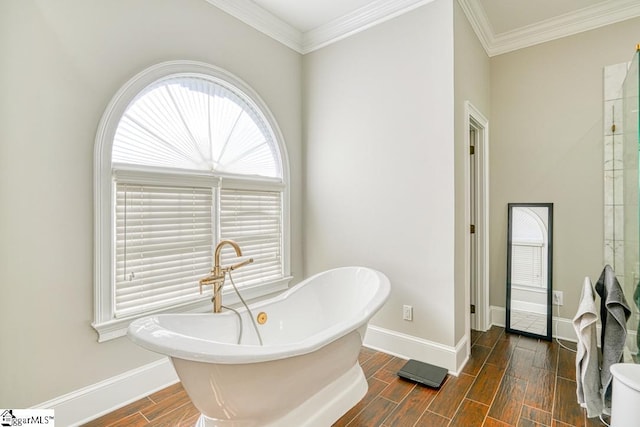 full bath featuring wood finish floors, baseboards, a freestanding bath, and ornamental molding